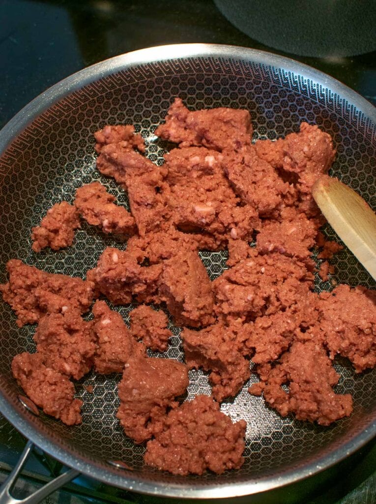 Ground beef being browned in a frying pan on the stove top.