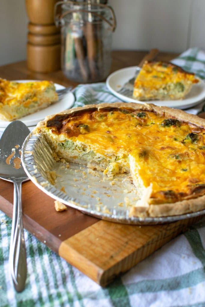 A cheese and broccoli quiche with 2 slices removed and placed on plates.