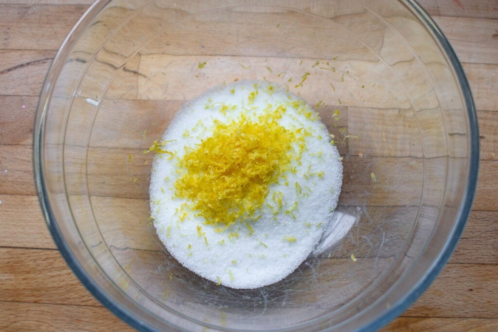 Lemon rind added to granulated sugar in a large mixing bowl.
