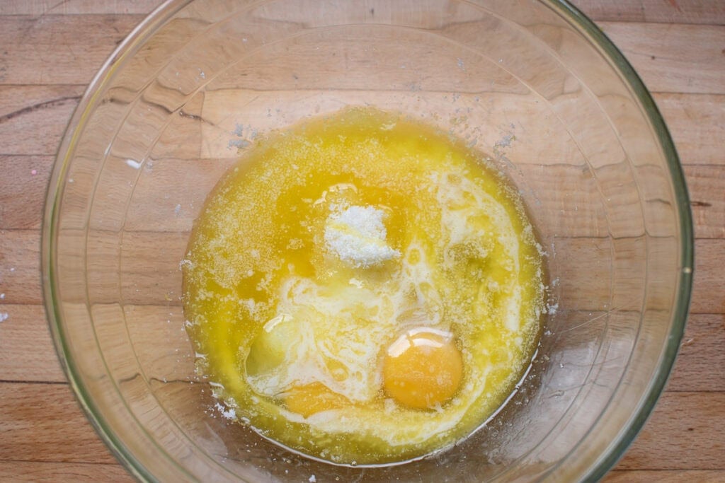 Eggs, melted butter and lemon juice added to a large bowl of lemon sugar.