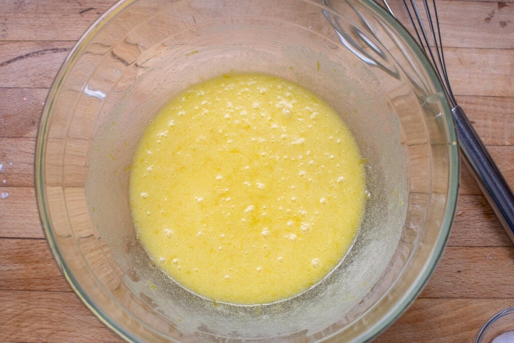 Melted butter and lemon sugar mixture whisked together in a large glass mixing bowl.