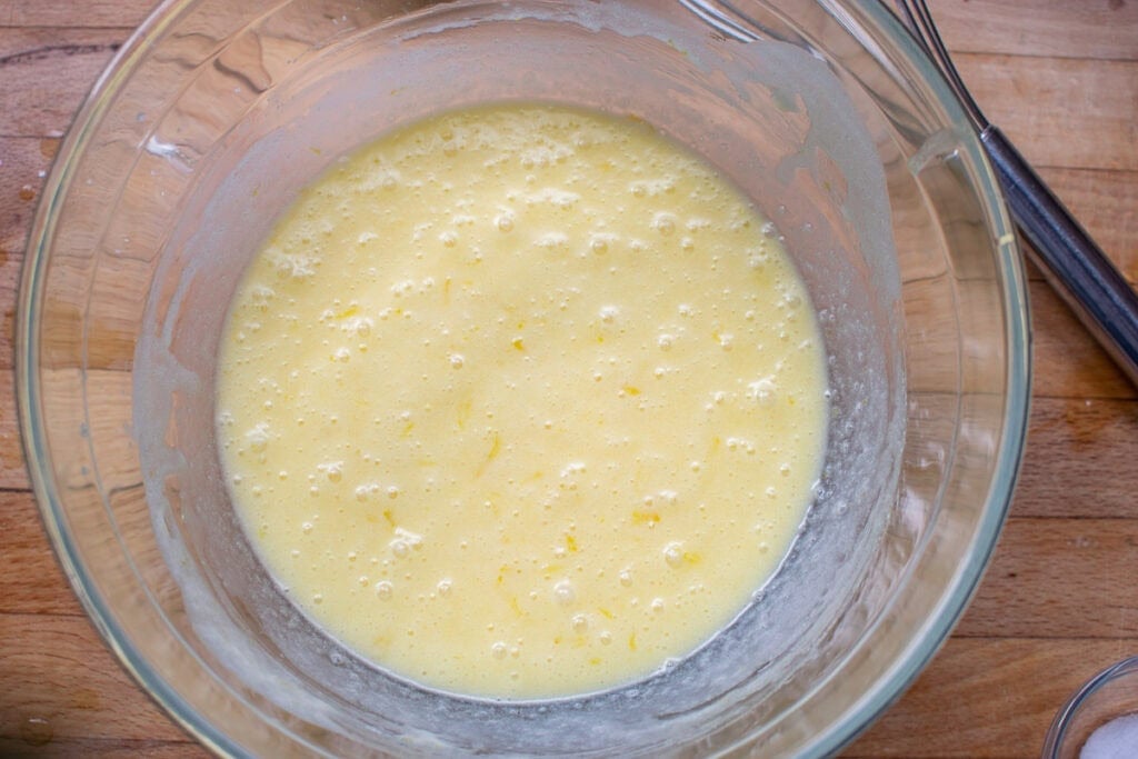Milk whisked into the butter, lemon juice, egg and sugar mixture for lemon and raspberry muffins.