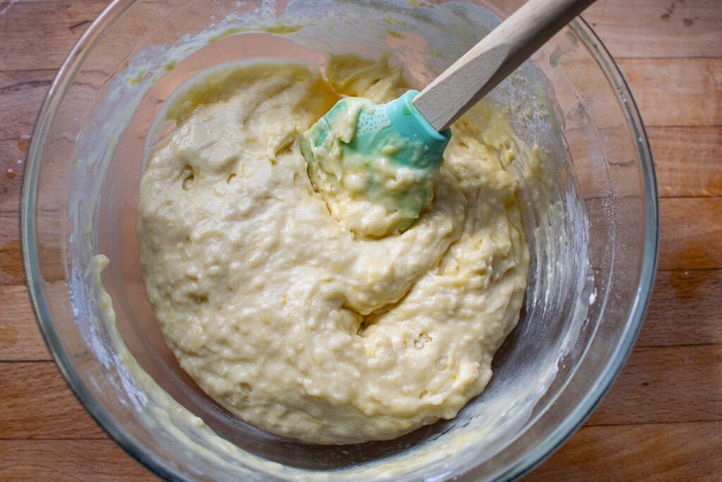 Dry ingredients stirred into the wet ingredients for lemon and raspberry muffins.