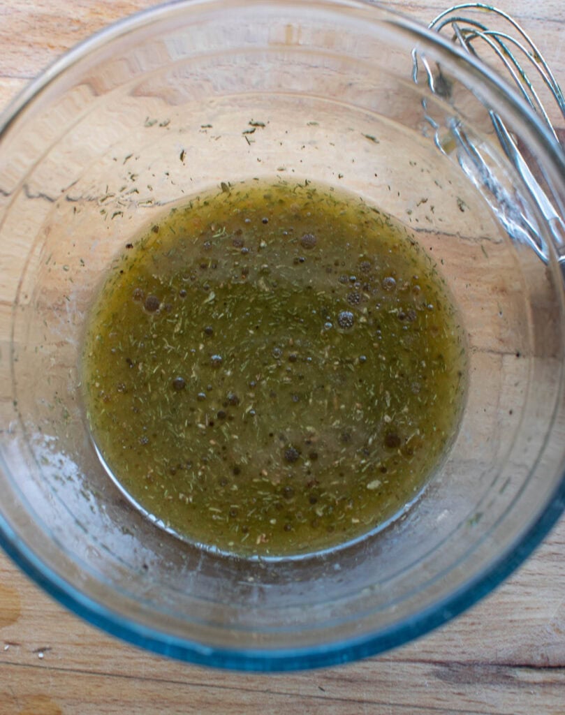A lemon vinaigrette dressing whisked together in a small glass bowl.