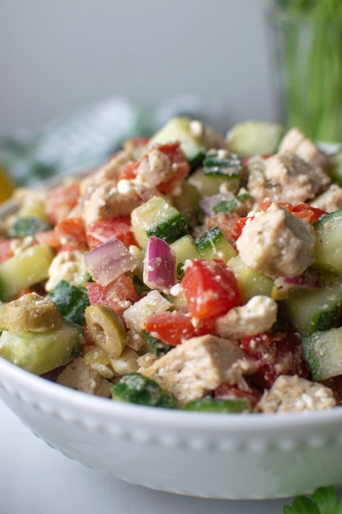 A large bowl of mediterranean salad with chicken and feta cheese.