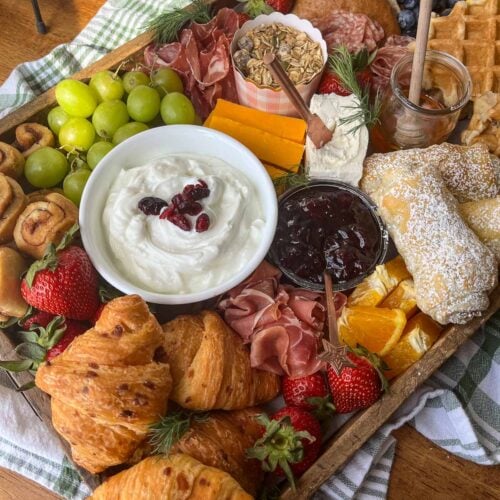 A brunch charcuterie board with a selection of breads, pastries, cheeses and meats.
