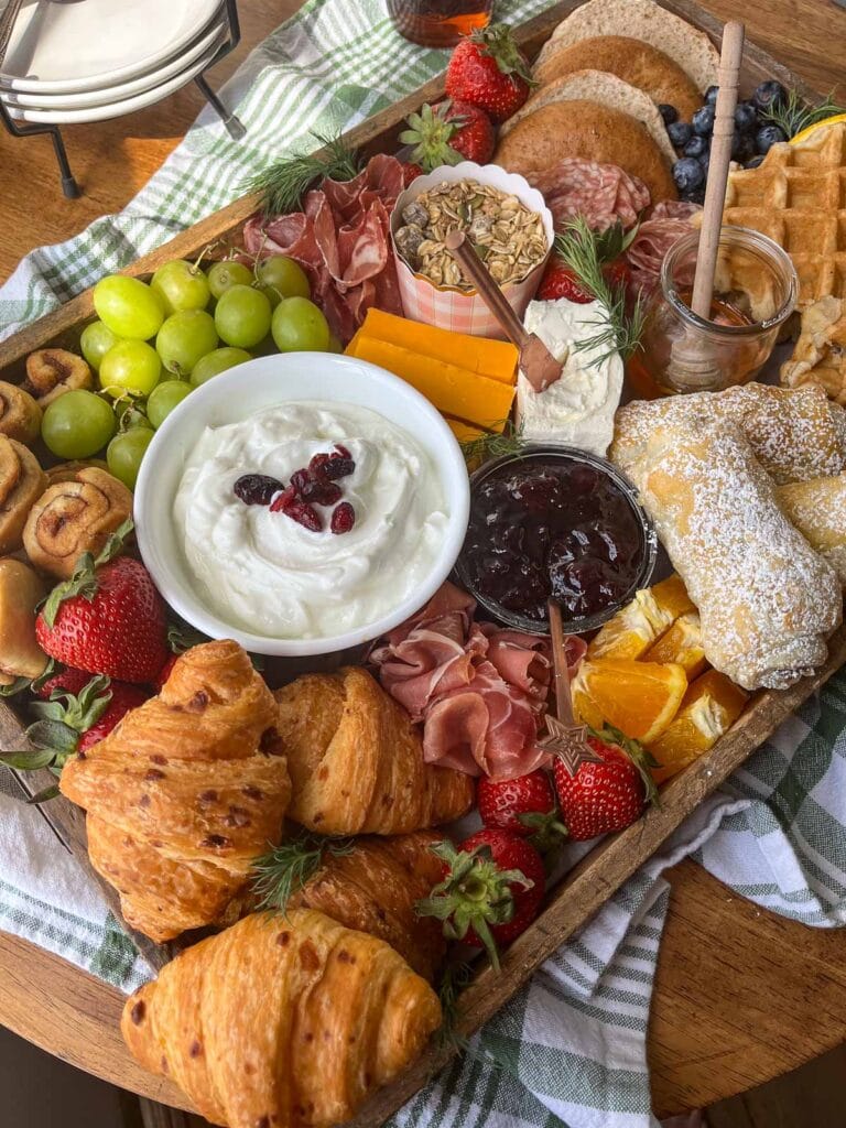 A brunch charcuterie board with a selection of breads, pastries, cheeses and meats.