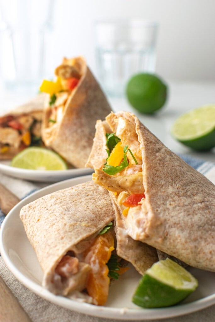 Two chicken fajitas cut in half to show the chicken and bell pepper filling.