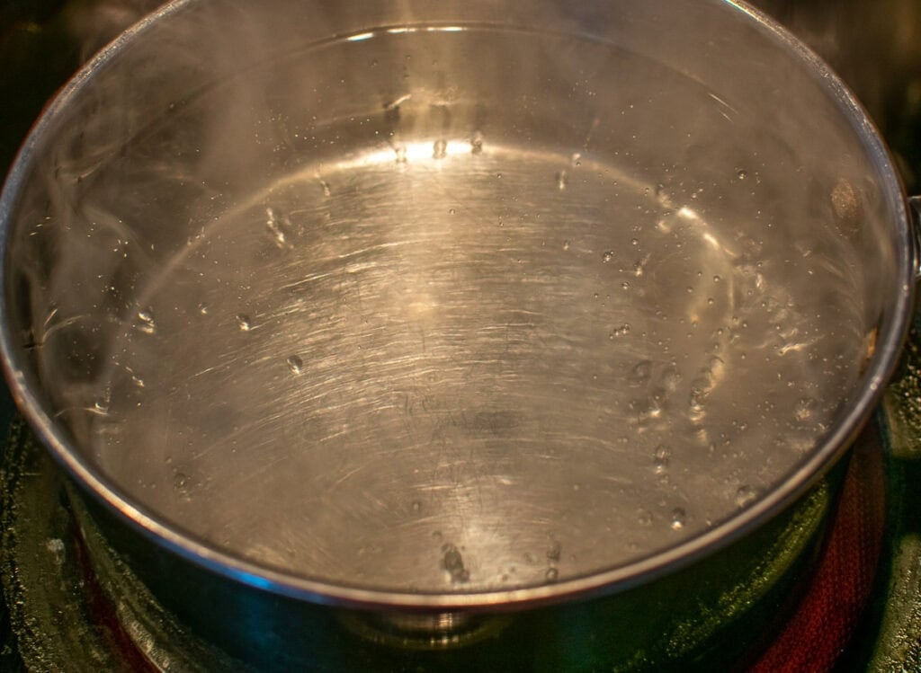 A pot of rapidly boiling water on the stove top