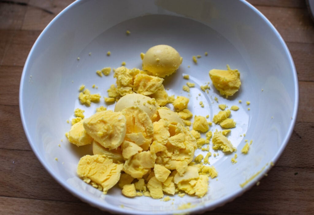 Egg yolks from hard boiled eggs in a white bowl.