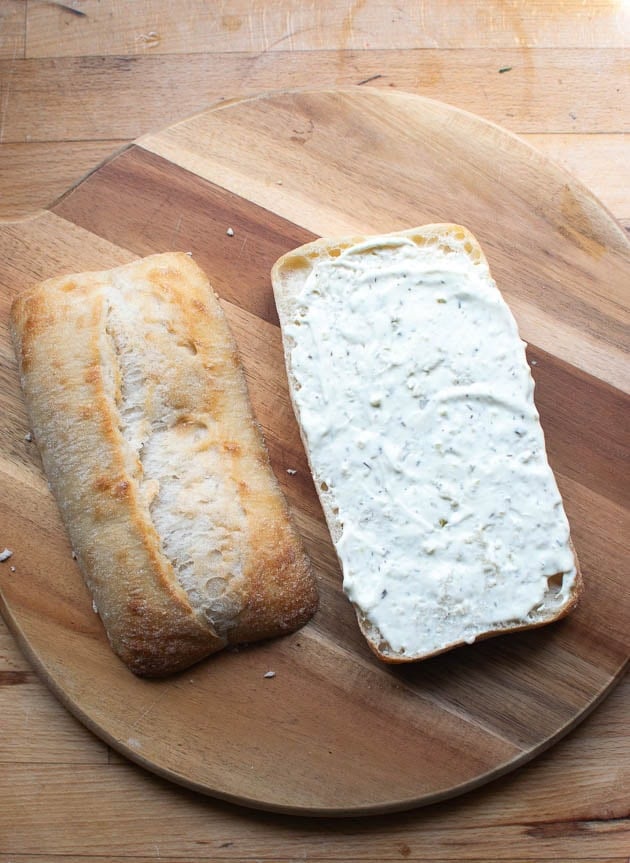 Large ciabatta bun cut in half, with tarter sauce spread over the bottom half.