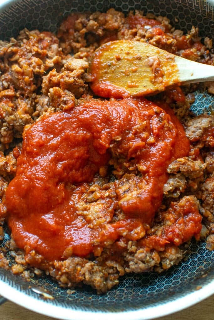 Cheeseburger mixture made with ground beef, tomato sauce, spices chopped onion prepared in a frying pan.