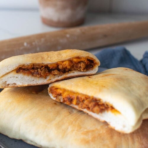 Two cheeseburger hand pies stacked on top of each other with the top one cut in half to show the cheeseburger filling.