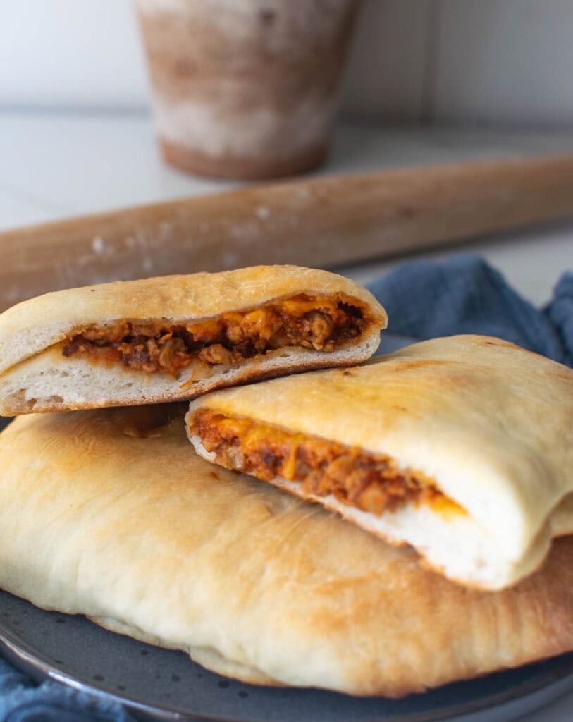 Two cheeseburger hand pies stacked on top of each other with the top one cut in half to show the cheeseburger filling.