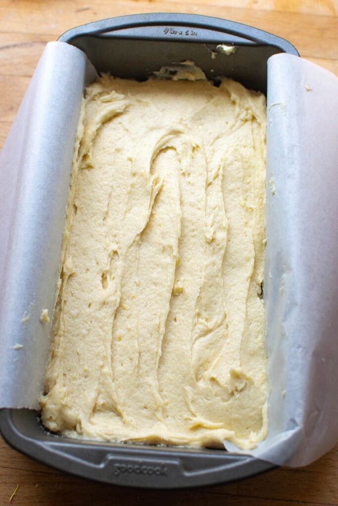 Classic pound cake batter in a loaf pan lined with parchment paper before baking.