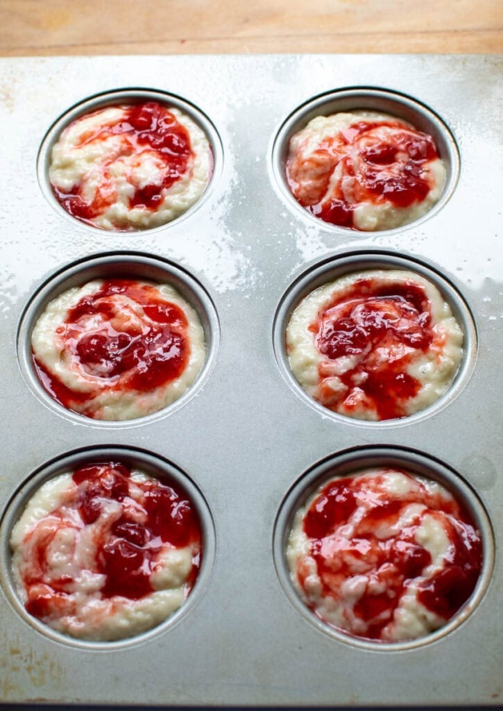Strawberry swirl muffins batter in muffin tins before baking.