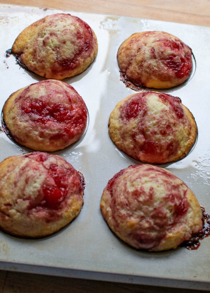 Freshly baked strawberry swirl muffins still in the muffin tins.