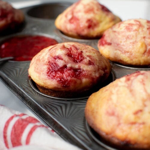 Freshly baked strawberry swirl muffins in an antique muffin pan.