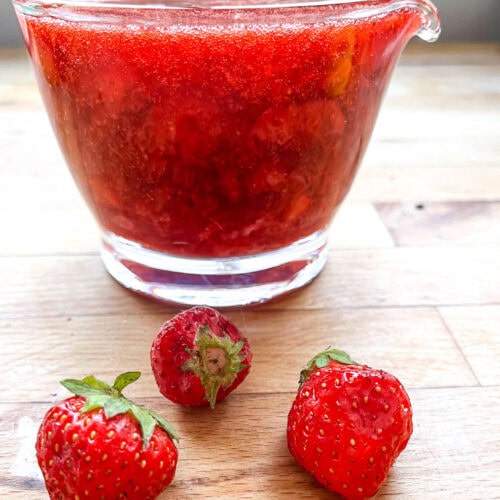 A small glass pitcher filled with homemade strawberry sauce.