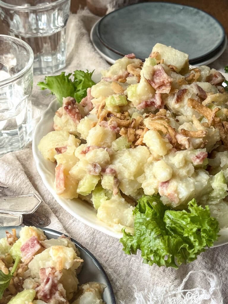 Creamy potato bacon salad in a serving bowl and garnished with lettuce leaves.