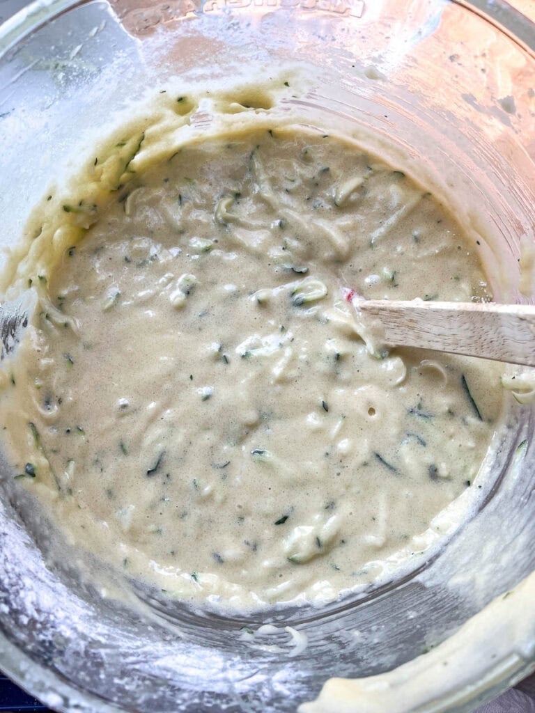 Grated zucchini folded into batter to make zucchini bundt cake.