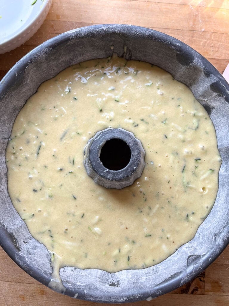Batter to make zucchini almond cake poured into a greased and floured bundt pan before baking.