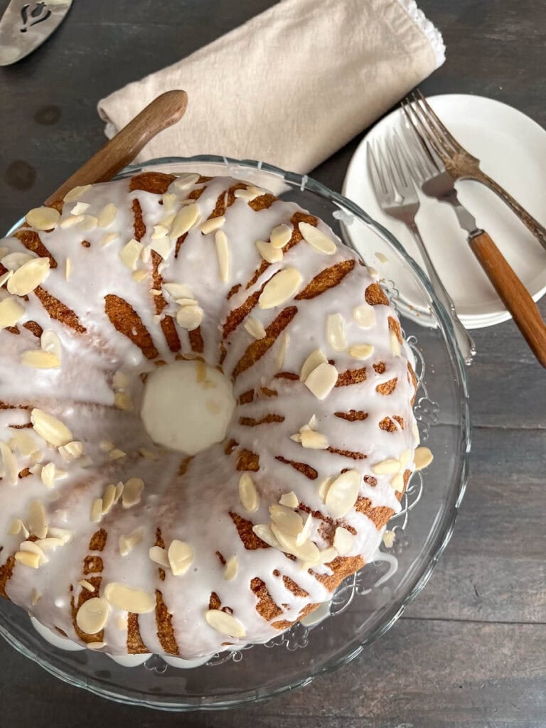An overhead image of an almond zucchini bundt cake glazed with almond glaze and sprinkled with sliced almonds.