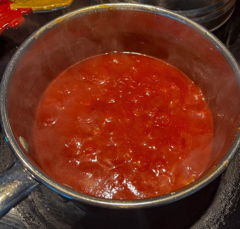 homemade barbecue sauce brought to a boil on the stove top in a saucepan.