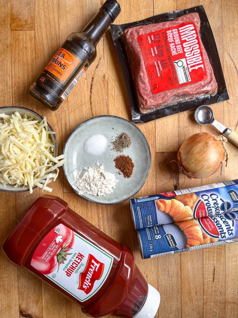 Ingredients to make Sloppy Joe casserole with crescent rolls including ground beef, shredded cheese, onion, ketchup, worcestershire sauce and refrigerated crescent rolls.