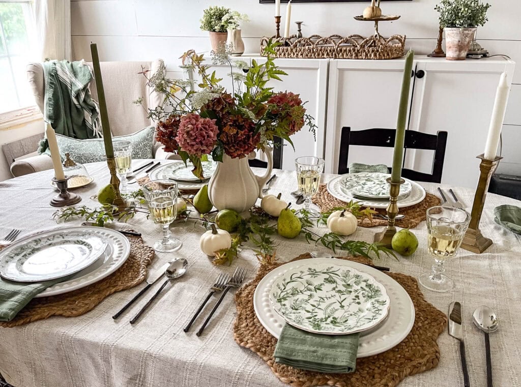 Fall tablescape ideas including a calming neutral colour palette of greens, linen and creams combined with dark burgundy hydrangeas and Queen Anne's lace arranged in a stone vase.