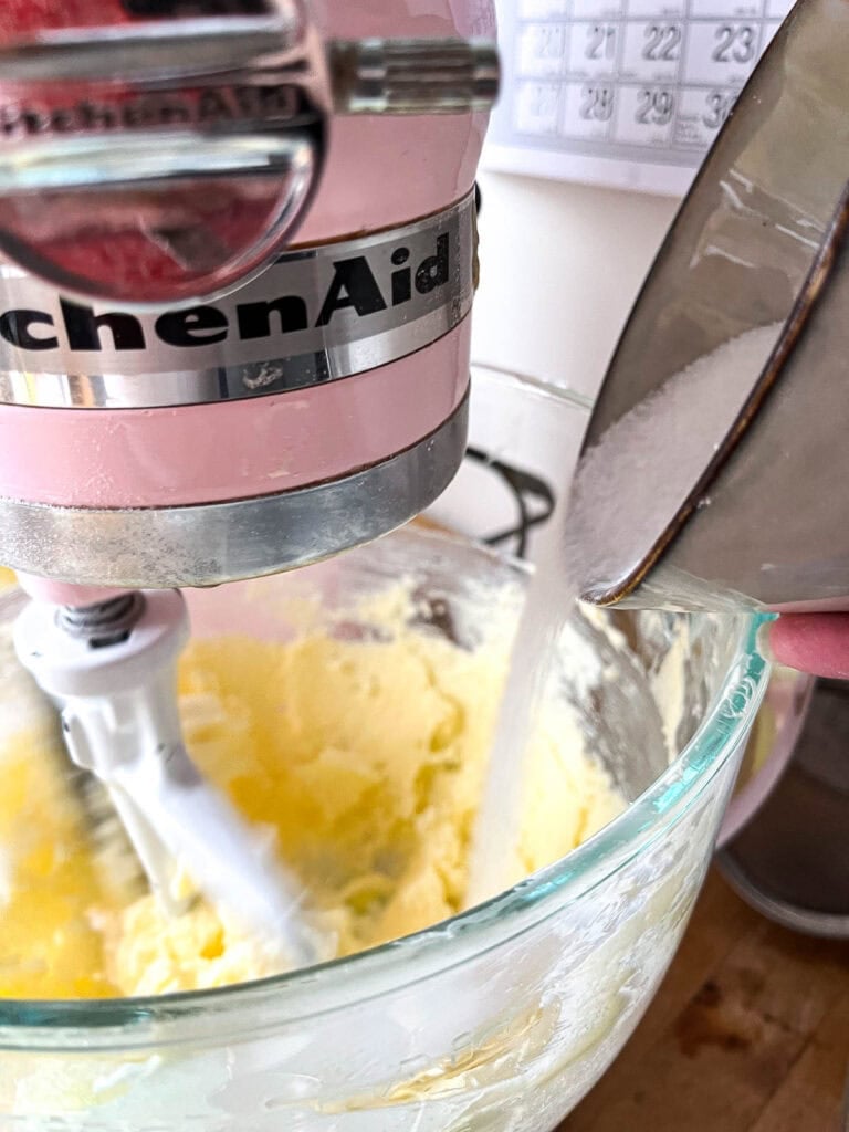 Sugar slowly been poured into creamed butter while the mixer is on low.