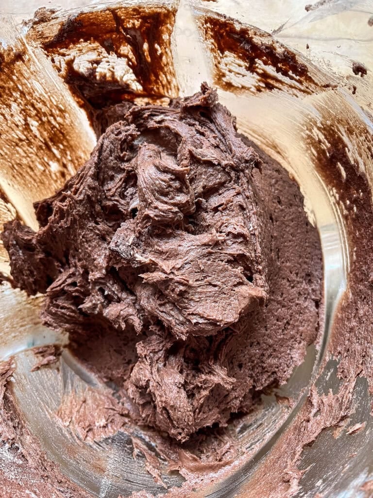 Batter to make chocolate chip brownie cookies in the bowl of an electric mixer ready to be scooped onto the baking sheet.