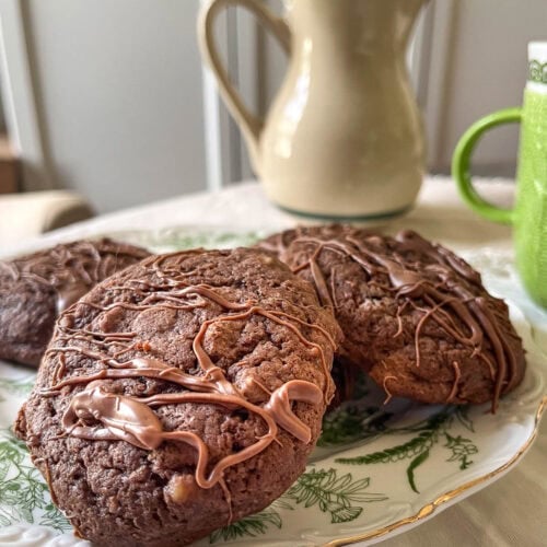 A plate of brownie chocolate chip cookies drizzled with melted chocolate.