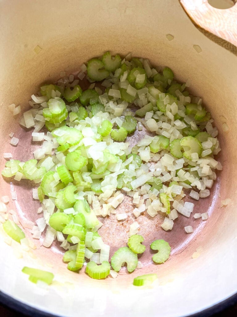 Chopped onions and celery cooking in olive oil in a dutch oven.