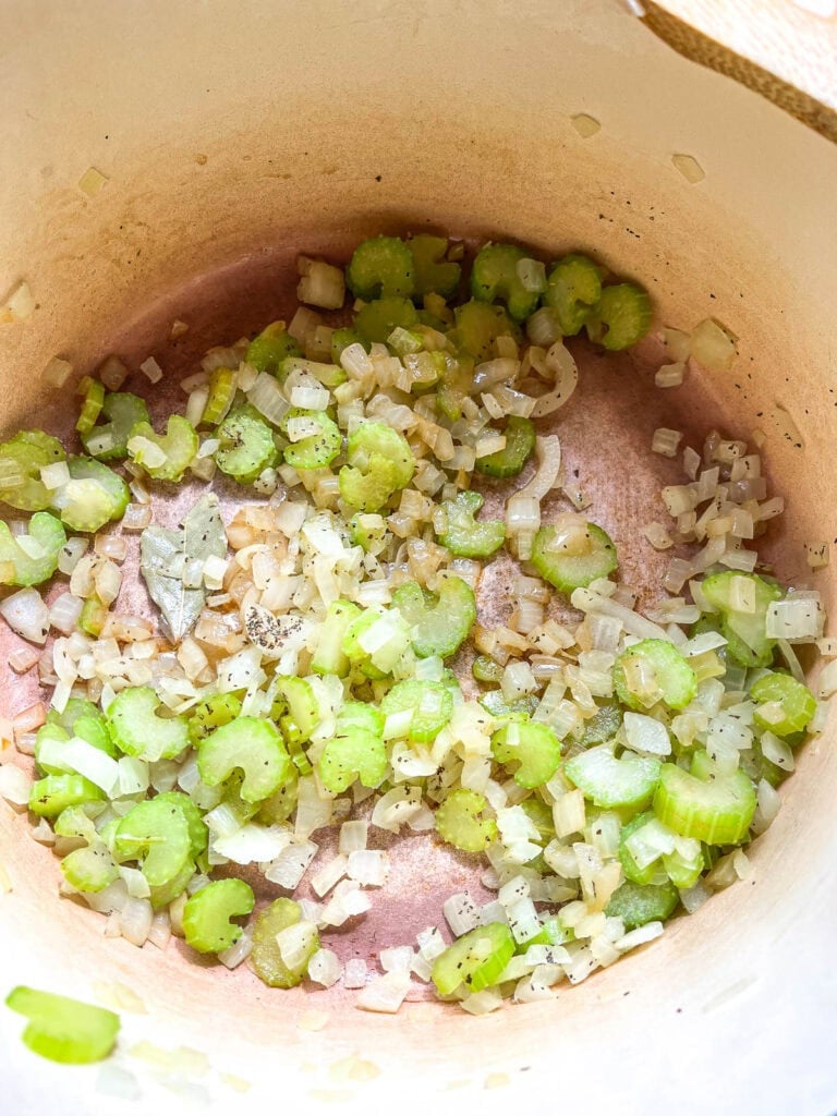 Onions and celery in a dutch oven that have been softened, with basal, salt and Worcestershire sauce and bay leaf stirred in.