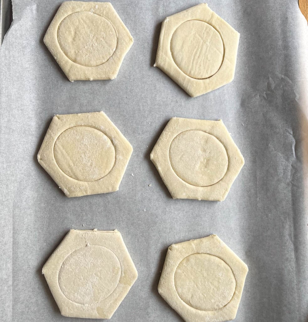 Frozen puff pastry shells on a parchment lined baking sheet.