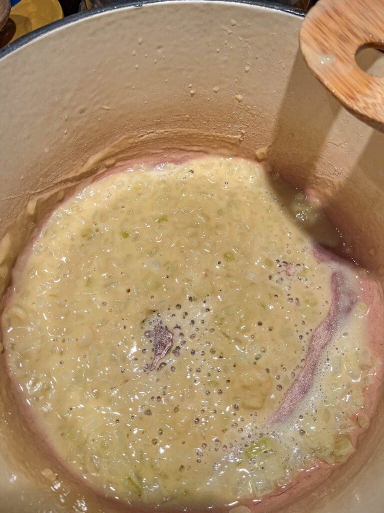Flour added to softened onion and butter mixture in a dutch oven to make a roux.