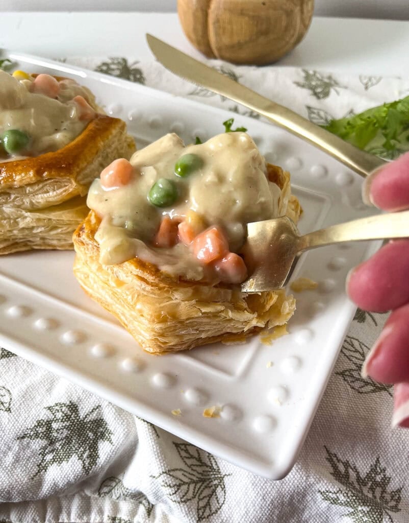 Chicken pot pie in puff pastry shell with a fork digging Into it.