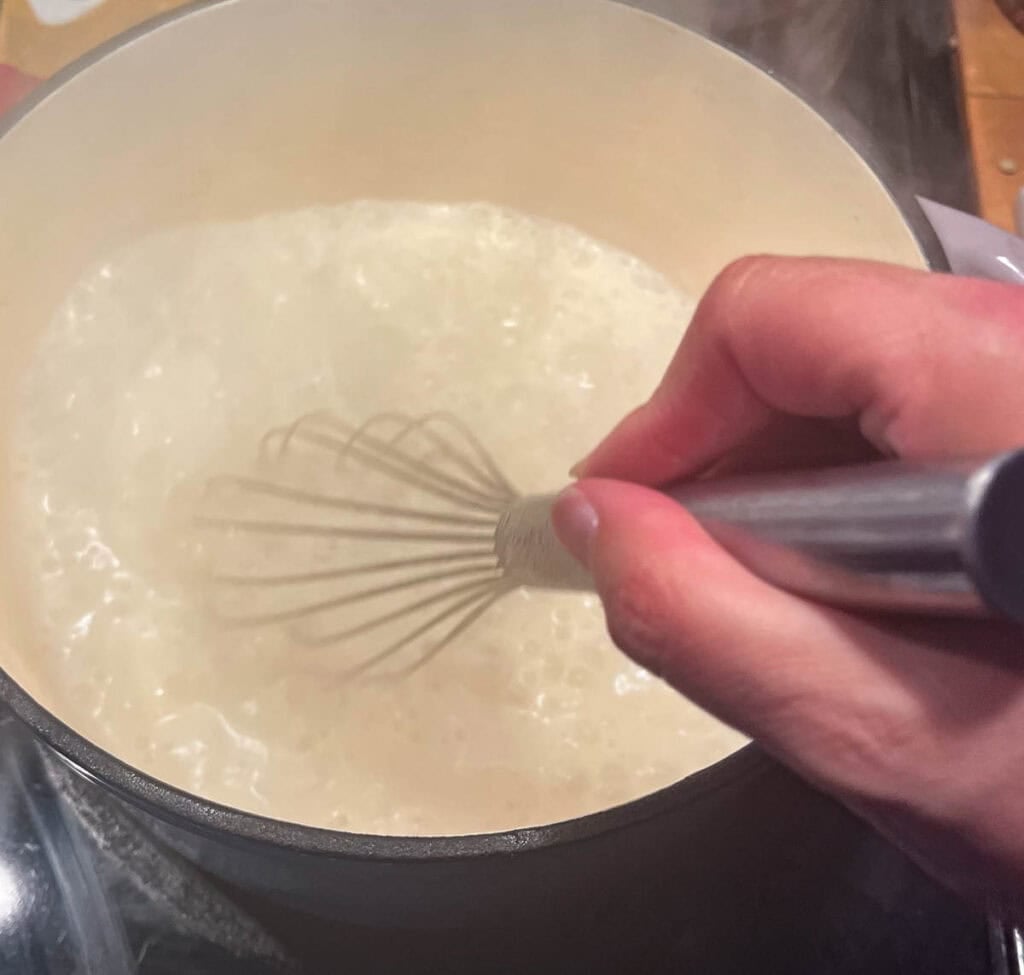 Milk and reserved potato water added to the onion, celery, flour mixture to create the creamy base for corn and potato chowder.