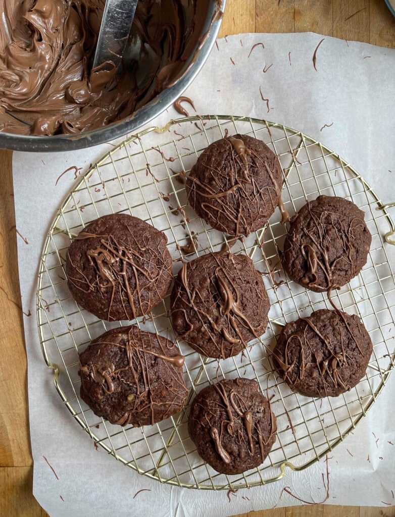 Browie cookies drizzled with melted chocolate on a gold round wire rack with parchment paper underneath.