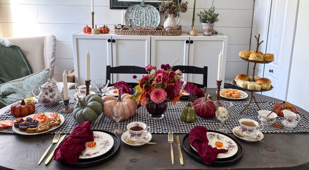 A dinner table set for a Halloween Tea Party in shades of burgundy, orange, green and cream.