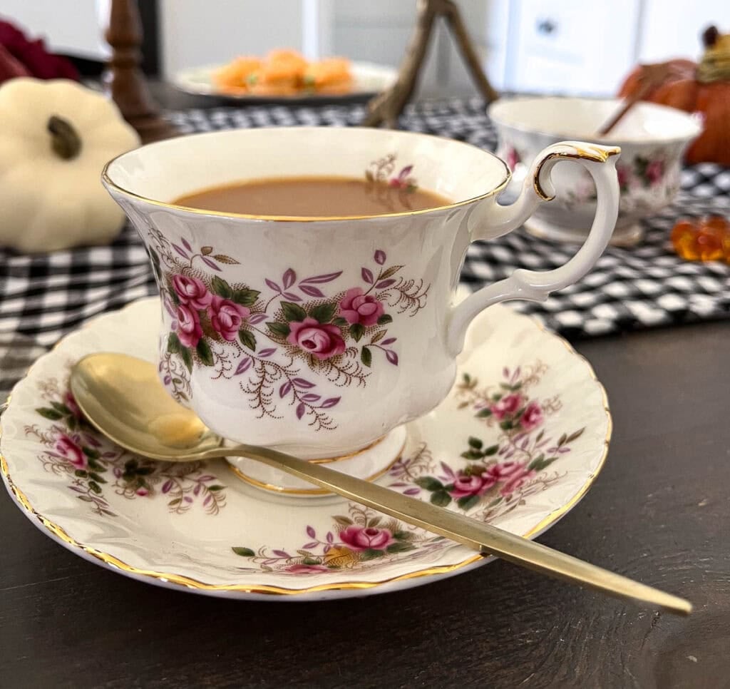 A cup of tea on a matching saucer with a spoon resting on the saucer.