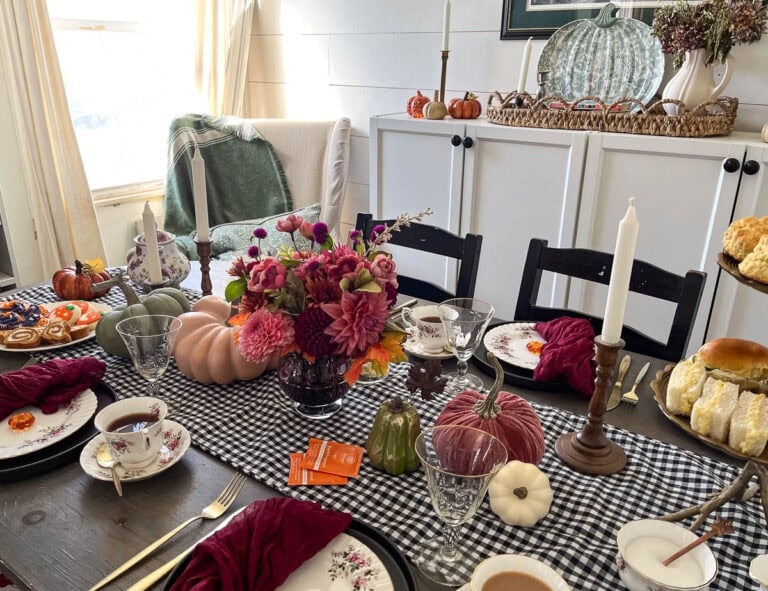 A dining room table set for an afternoon Halloween Tea in shades of purple, orange, green and green.